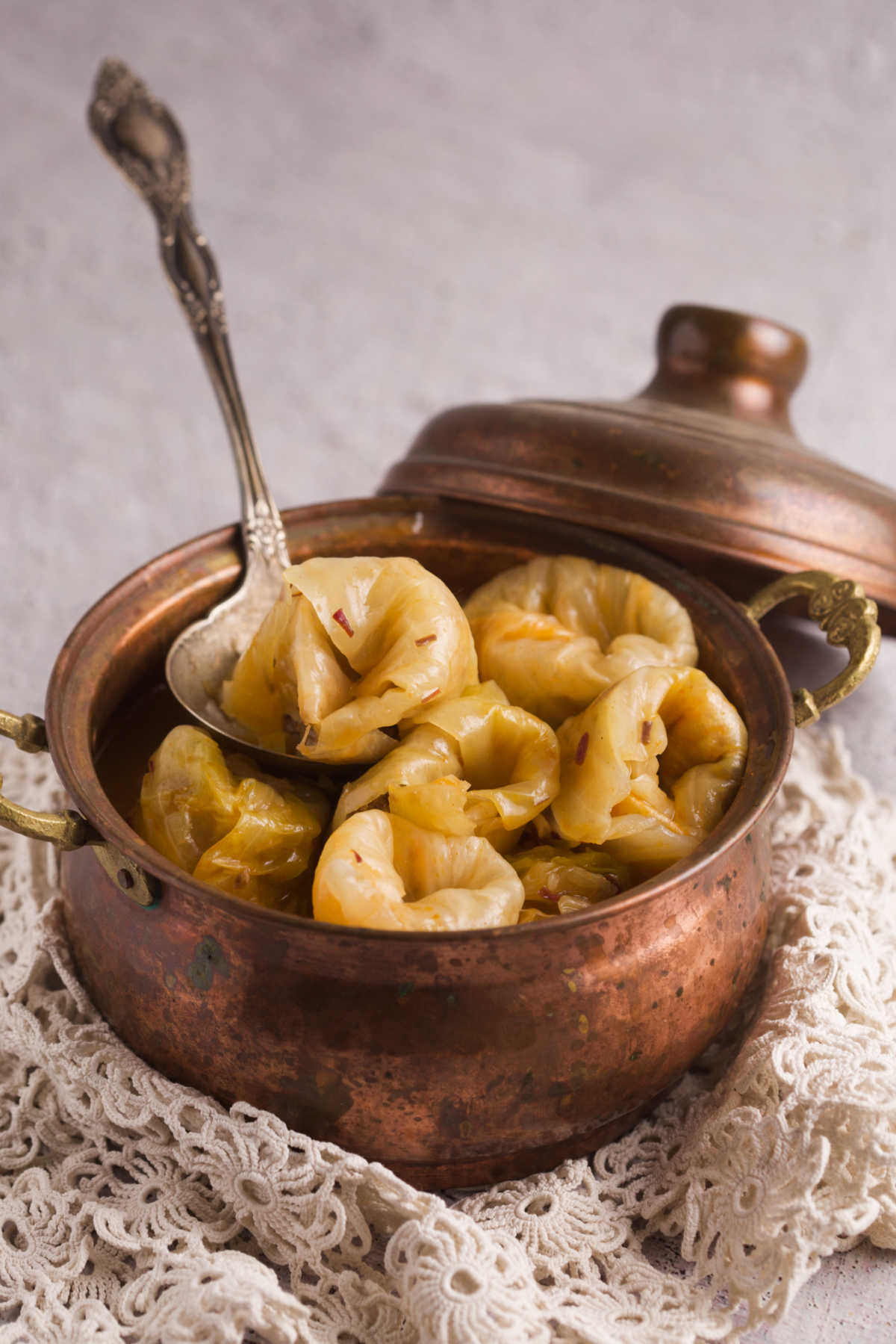 Stuffed cabbage on a spoon in a copper pot. 